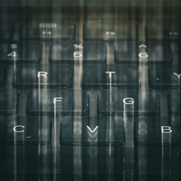 Close-up of a blurred laptop keyboard with visible keys and reflections.